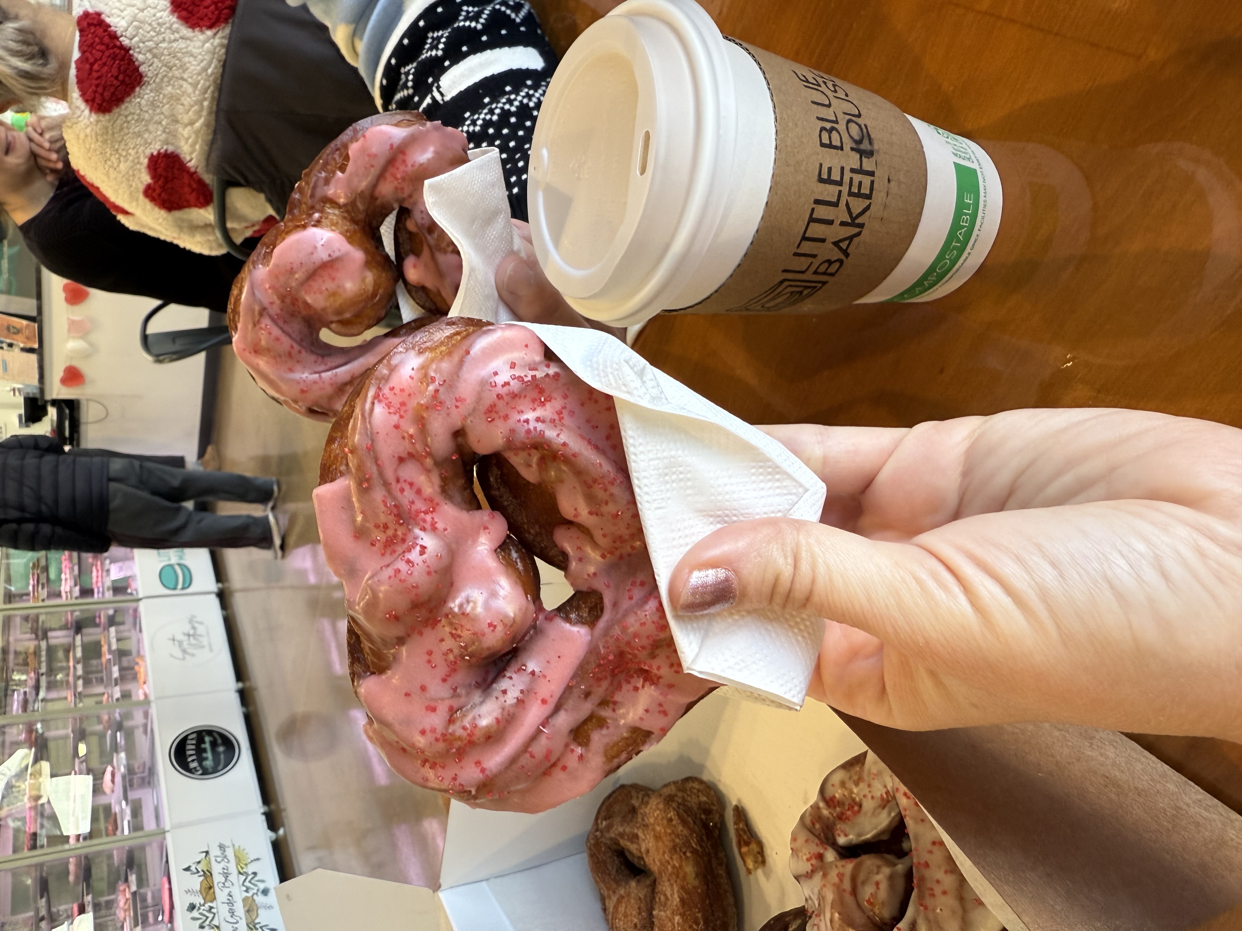 Heart-shaped crullers with pink glaze from The Blue Ox Bakery, held in a napkin at Little Blue Bakehouse